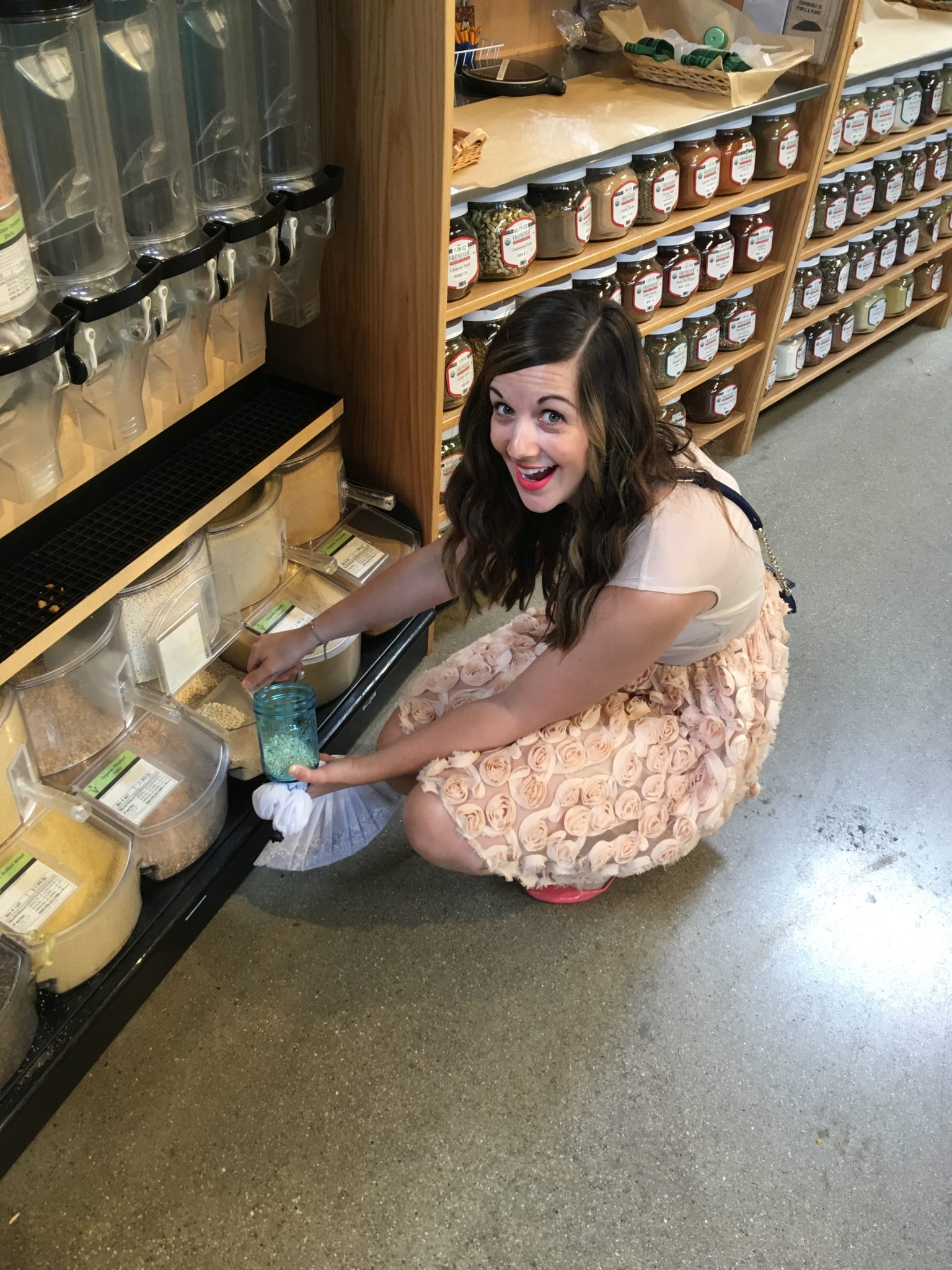 girl in pink dress in front of bulk food canisters in store
